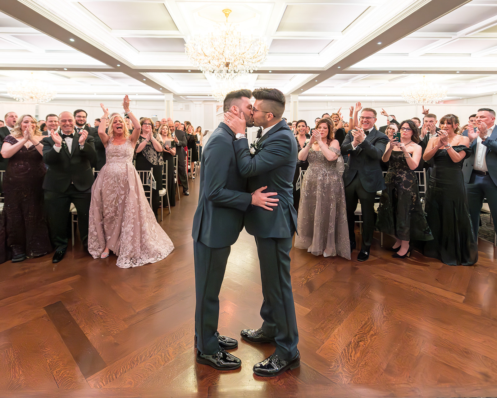 grooms kissing at indoor ceremony
